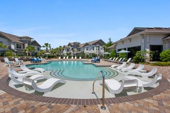 a swimming pool with white chairs in front of some apartments